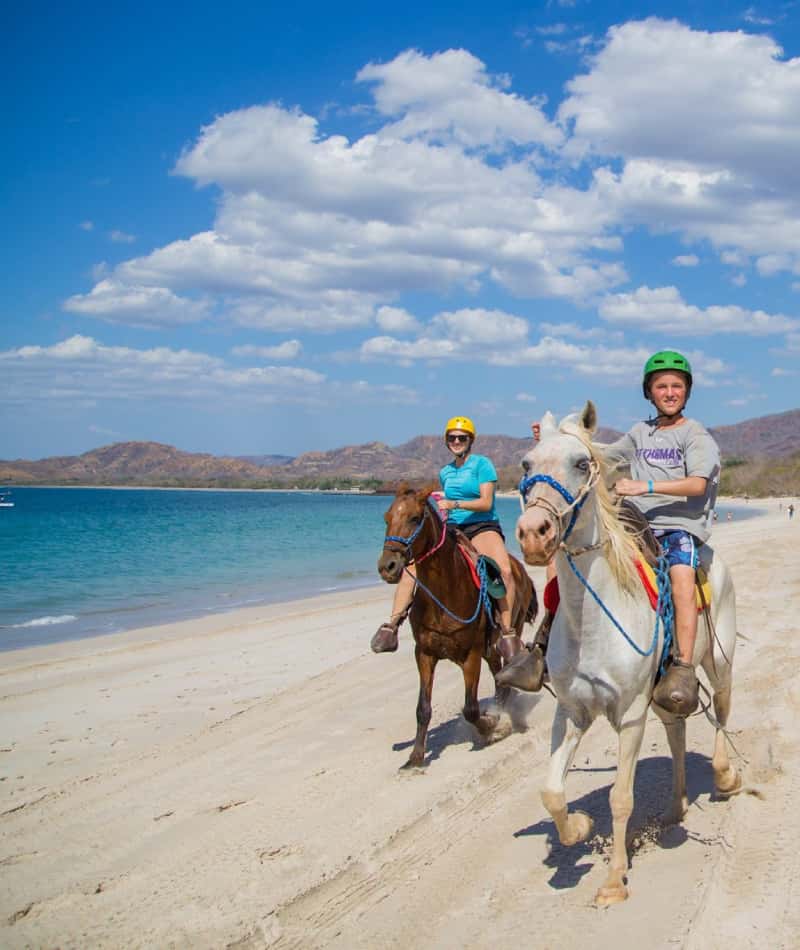 Horseback Riding Tour Playa Conchal 02 a man an a child riding horses on the beach